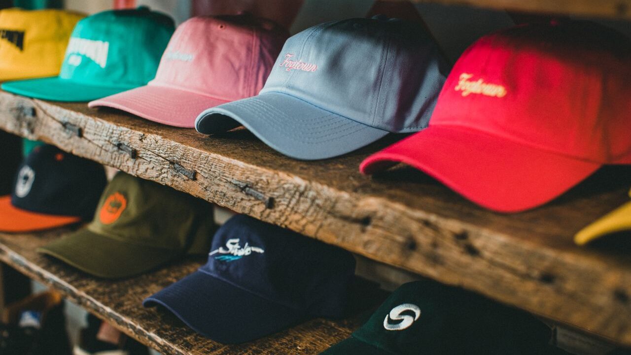 A variety of colorful baseball caps arranged on rustic wooden shelves in a store setting.